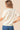 Woman wearing a cream sweater and blue jeans against a beige background