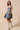 Model side view of denim flare dress with soft waist shape and texture