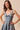 Woman wearing a denim dress with a bow detail on a beige background