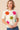 Woman wearing a white sweater with colorful flower patterns on a beige background