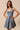 Woman wearing a denim dress with a bow detail on a beige background