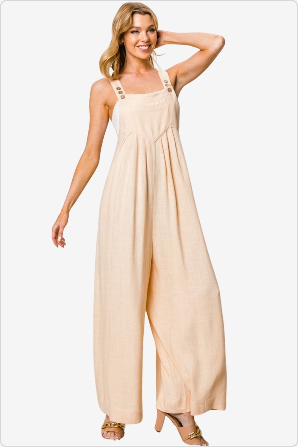 Confident woman posing in a beige linen jumpsuit with button details, perfect for summer