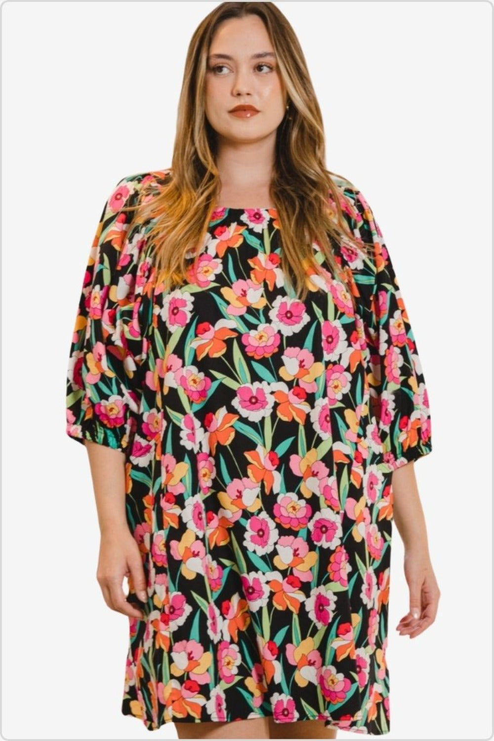 Fashionable plus-size model in a floral puff sleeve mini dress with vibrant spring pattern.