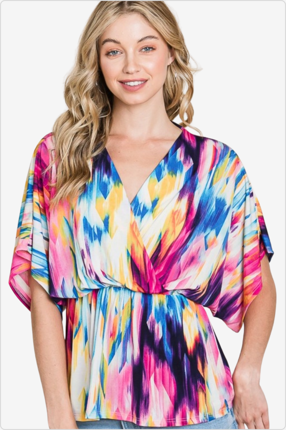 Smiling woman in a vibrant abstract print v-neck blouse with flowing sleeves, perfect for a colorful spring look.