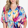 Smiling woman in a vibrant abstract print v-neck blouse with flowing sleeves, perfect for a colorful spring look.