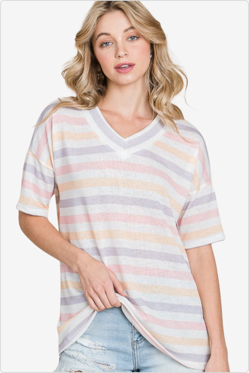Portrait of a woman in a pastel striped v-neck t-shirt, paired with light denim, perfect for a relaxed summer outfit.