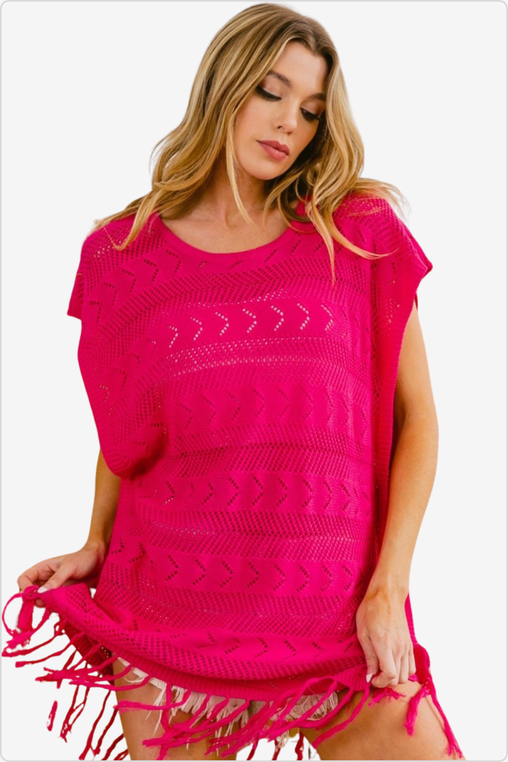 Woman modeling a bright fuchsia fringed hem knit top.