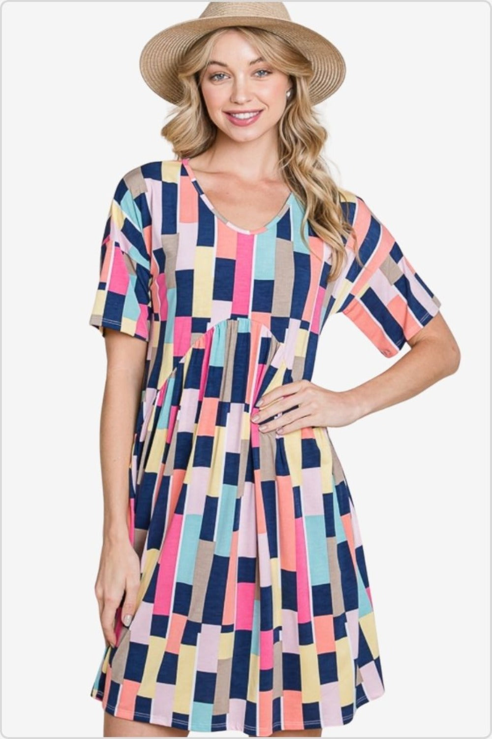 Woman in a straw hat smiling in a colorful geometric print dress with short sleeves, perfect for a playful and chic summer look.
