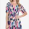 Woman in a straw hat smiling in a colorful geometric print dress with short sleeves, perfect for a playful and chic summer look.