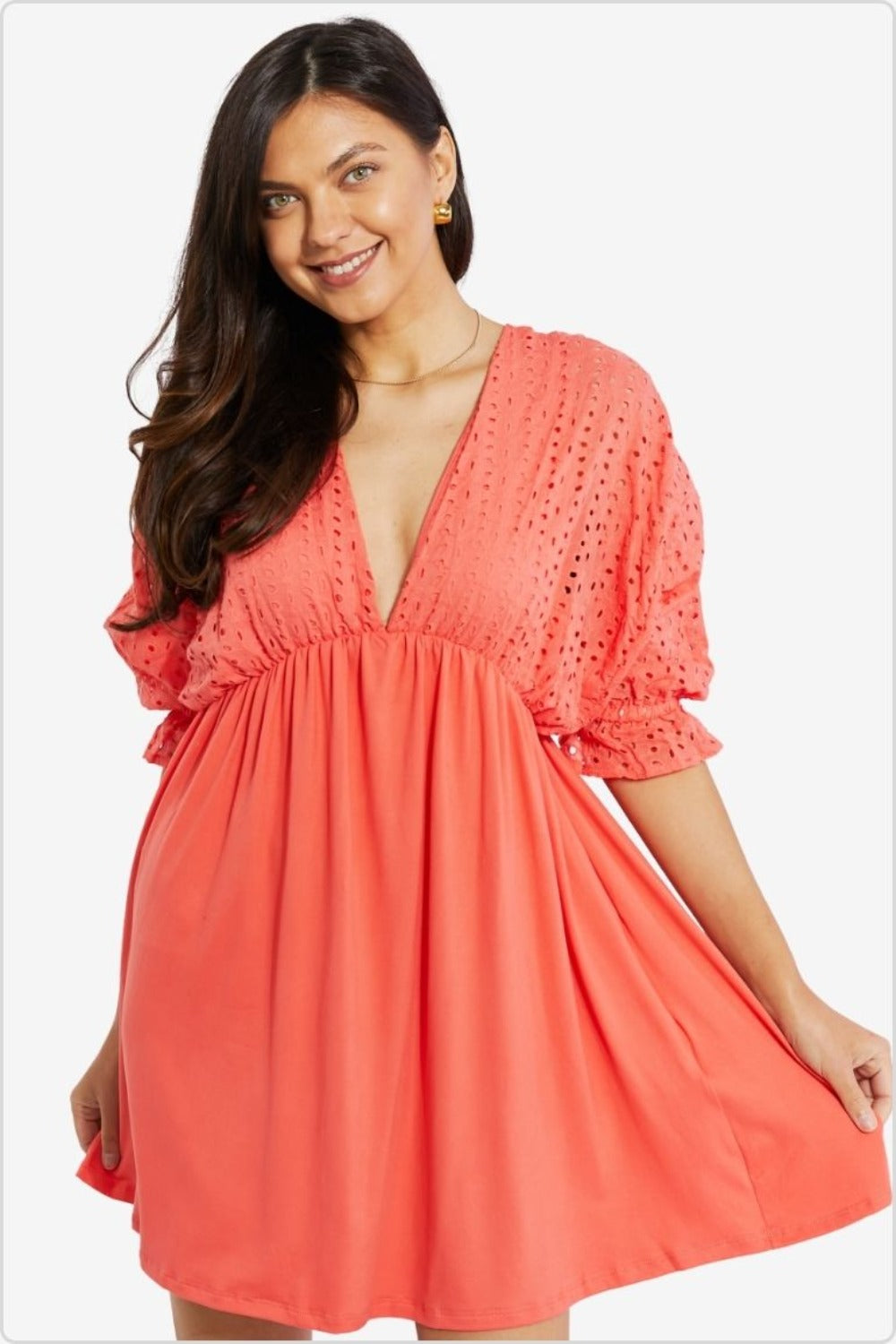 Woman in a coral dress with eyelet embroidery and puff sleeves, embodying a breezy, bohemian summer style.