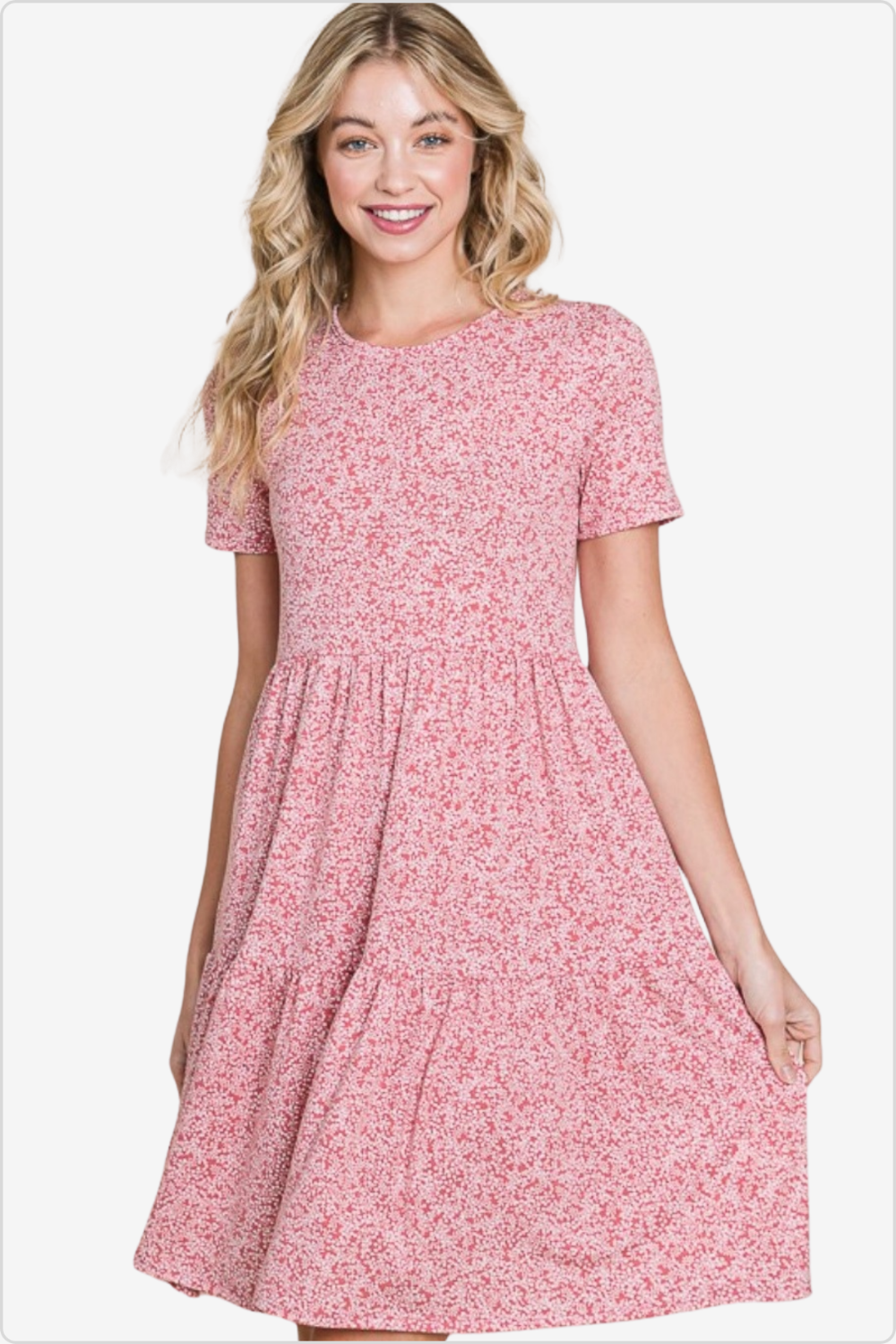 Joyful woman in a delicate pink floral print skater dress with a round neck and short sleeves, epitomizing soft summer elegance.