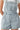 Close-up of soft denim fabric, square neck, and ruffled shoulder design.