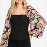 Woman in black corset top with vibrant floral balloon sleeves