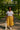 Striped tee styled with a mustard skirt, canvas tote bag, and white sneakers in the park