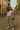 Striped tee styled with zebra pants, white boots, green quilted purse, and gray cap