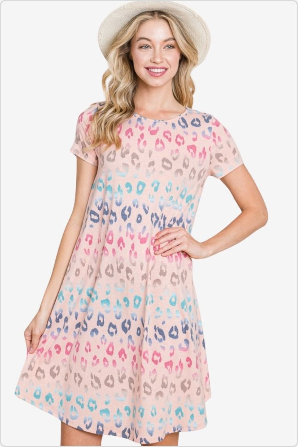Cheerful woman in a straw hat wearing a pastel-toned leopard print dress with short sleeves, perfect for a summery day out.