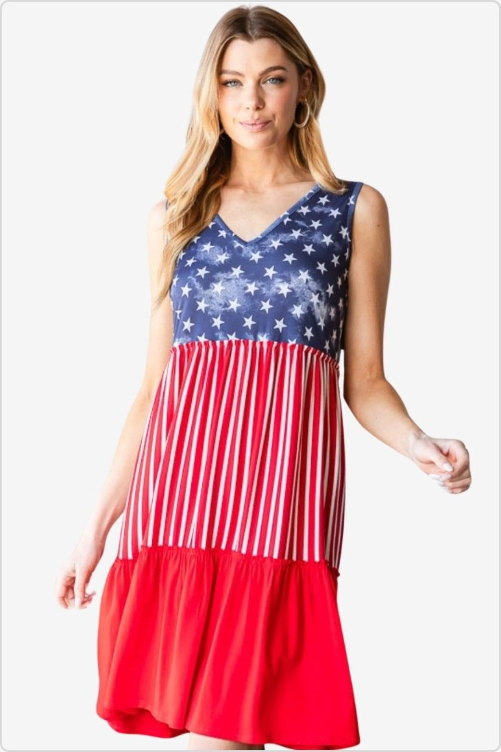 Woman in a sleeveless summer dress with American flag pattern, featuring stars on blue top and stripes on red skirt.