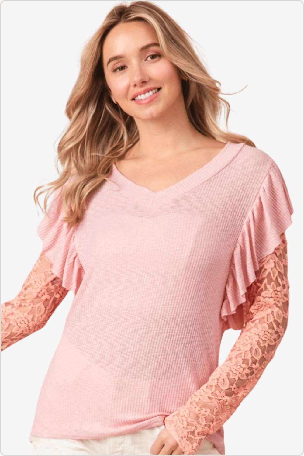 Smiling model in a pink rib knit top with v-neck and elegant ruffled lace sleeves.