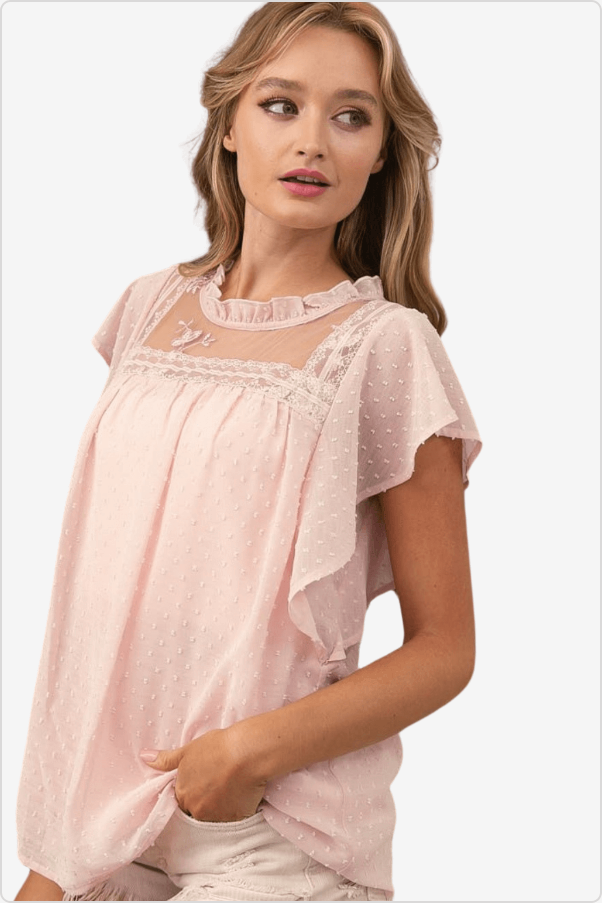 Woman in a soft pink blouse with delicate lace detailing and flutter sleeves.