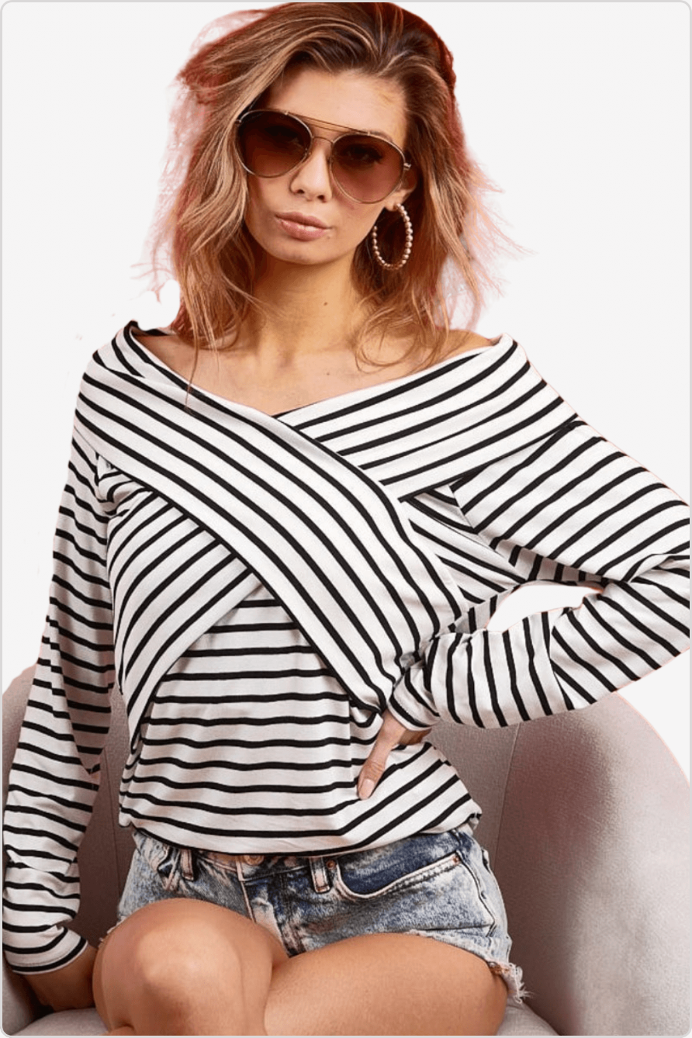 Chic model in a black and white striped crisscross long sleeve blouse, with trendy sunglasses and earrings.
