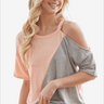 Smiling woman wearing a peach and grey color block round neck short sleeve t-shirt.