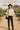 Romantic styling of eyelet blouse with black faux-leather pants and wide hat