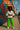 White peplum top styled with neon green trousers, sneakers, and statement belt