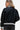 Rear view of a black PU leather bomber jacket with varsity-inspired collar and ribbed hem.