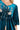 Deep teal velvet mini dress with embroidered floral design and tassel details.