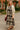 Model standing in abstract floral print midi dress with cream cardigan and brown heels, campus walkway.