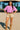 Woman in Acid Washed Oversized T-Shirt with beige shorts and suede boots, at festival stage, sunny day