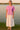 Woman in Acid Washed Oversized T-Shirt with white maxi skirt and beige sandals, at lake shore, sunset light