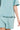 Close-up of dusty teal acid washed cotton fabric showing texture and stretch