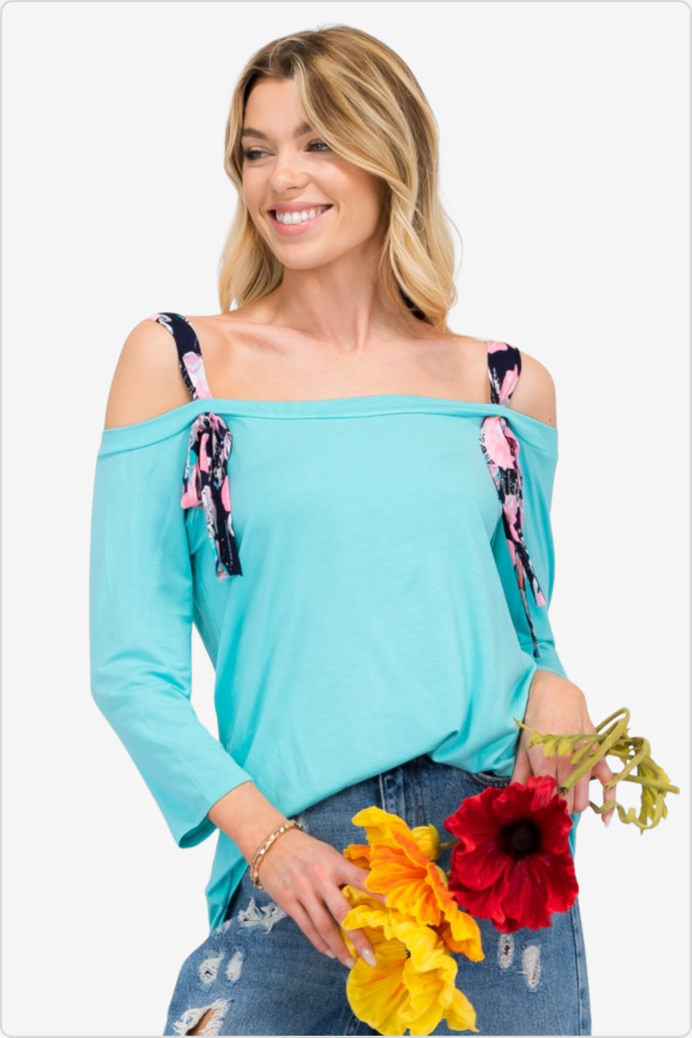 Radiant woman in aqua blue off-shoulder top with floral straps, fresh and summery style.