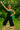 Model in black woven overalls with green knit bag, colorful sandals, and headscarf