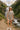 Model in striped taupe lounge set with baseball cap and sneakers on mountain trail