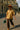Model in oversized striped shirt with brown pants, orange hat, and green mini bag