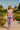 Model in color block ribbon top with lavender pants, red clutch, and headscarf