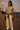 Woman in beige top and pants with green scarf at sunset