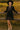 Woman in black babydoll dress with polka dots, plaid trim, tiered hem, standing in field at sunrise