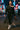 Woman in black fleece set with shorts, posing in cyber-cowboy accessories, urban sunset scene