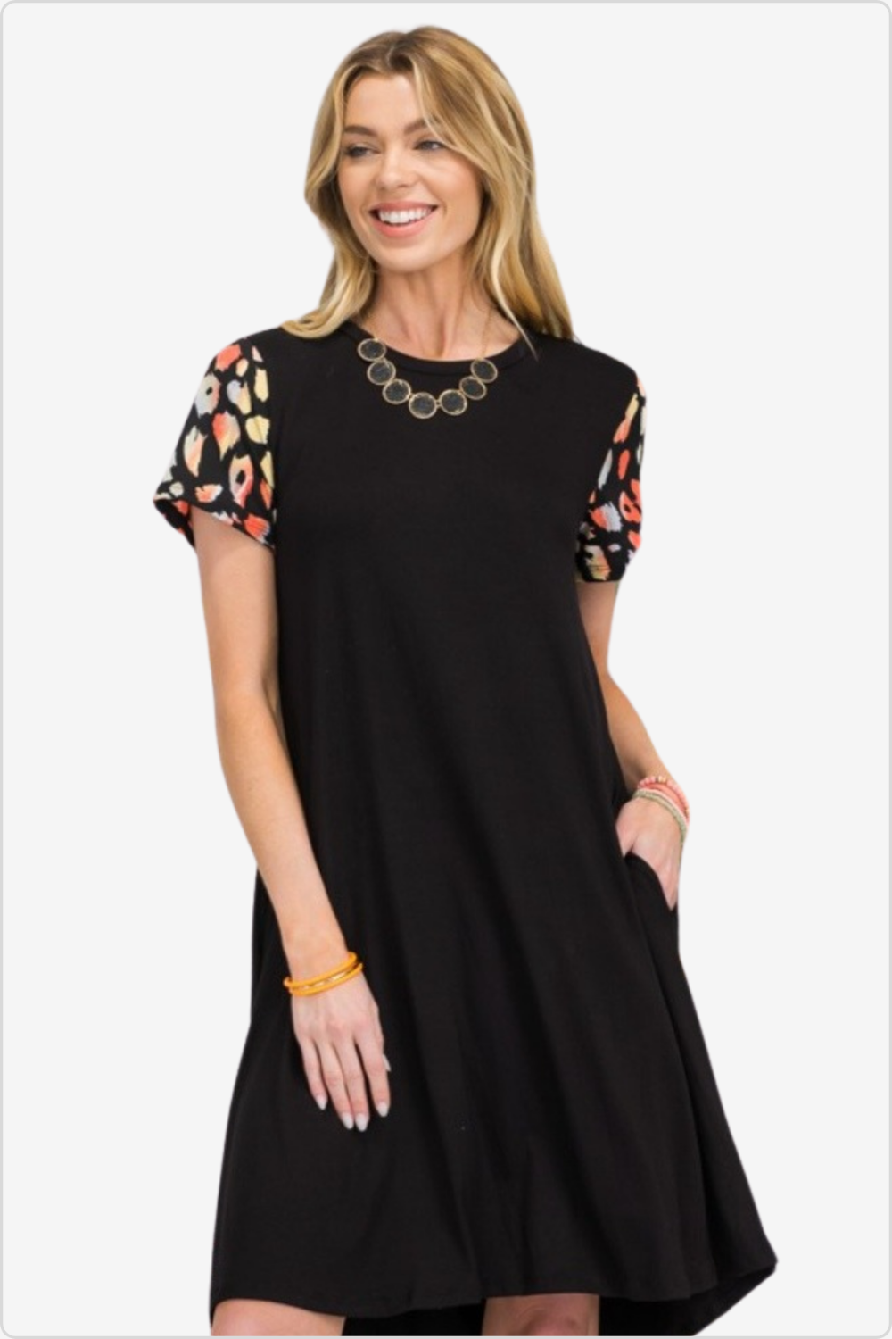 Smiling woman in a black shift dress with colorful floral sleeves, a chic casual ensemble.