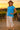 Standing in vineyard at sunset in blue ribbed tee with wide-leg linen pants and espadrilles, straw hat, warm golden light