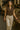 Walking by table in brown ruffle button top with beige jeans and brown belt, bookstall alley, soft daylight