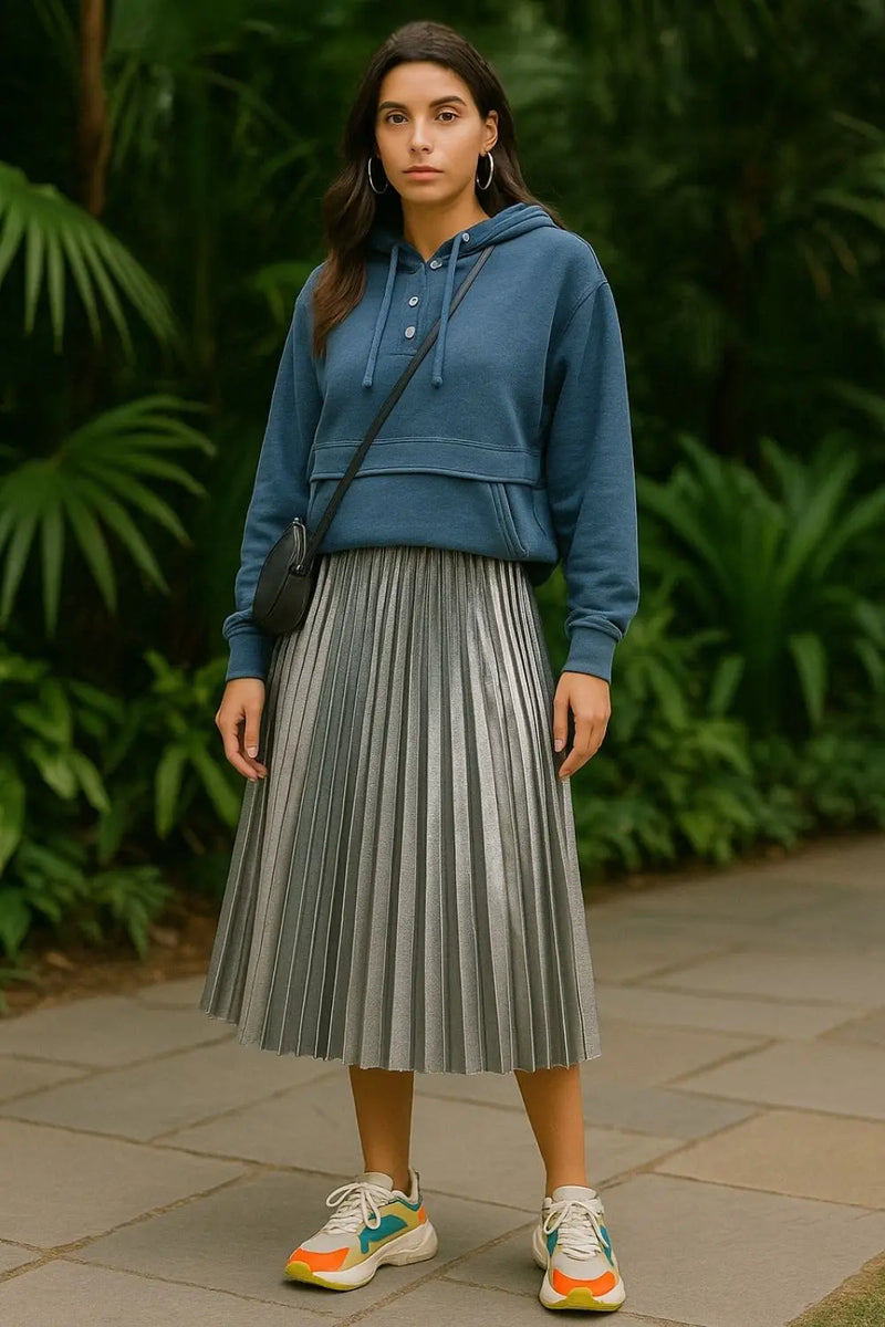 Blue snap hoodie styled with silver pleated skirt, crossbody bag, and color-block sneakers