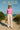 Cap sleeve tee styled with ivory trousers, straw hat, and beachside tote