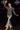 Woman dancing in charcoal ribbed half zip sweater with silver flared pants and heels, disco lights indoor.