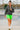 Model walking in charcoal ribbed half zip sweater with neon biker shorts and sneakers, skatepark graffiti.