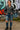 Woman posing in charcoal ribbed half zip sweater with ripped jeans and boots, graffiti wall background.