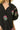 Close-up of pink floral embroidery on black fabric and neckline stitching.
